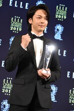 トロフィーを受け取りガッツポーズを見せる中村倫也。