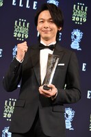 トロフィーを受け取りガッツポーズを見せる中村倫也。