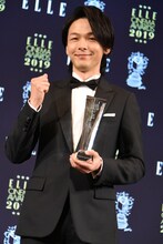 トロフィーを受け取りガッツポーズを見せる中村倫也。