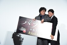 パネルを片付けながら退場するポン・ジュノ（左）とソン・ガンホ（右）。