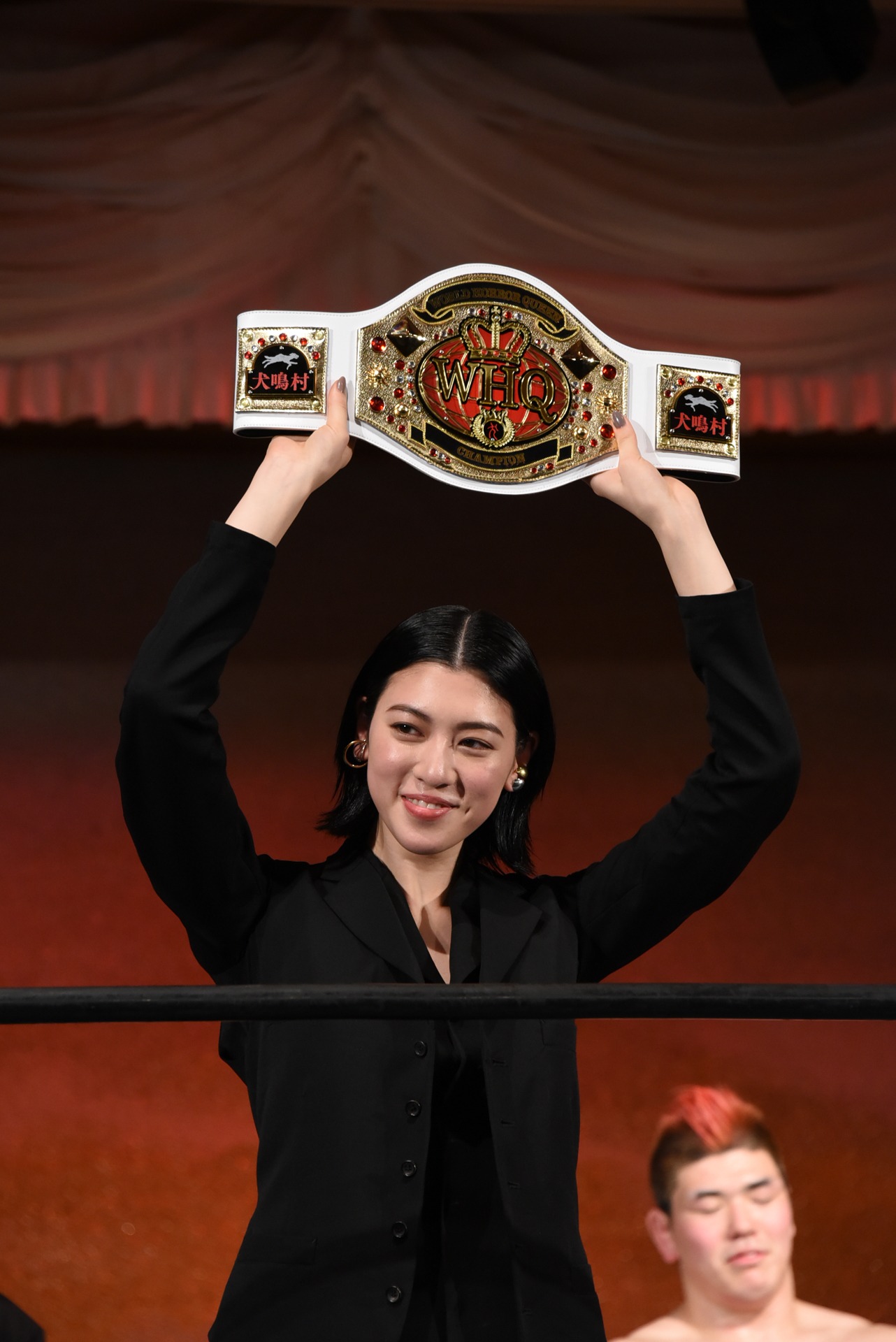 「WORLD HORROR QUEEN」のチャンピオンンベルトを掲げる三吉彩花。
