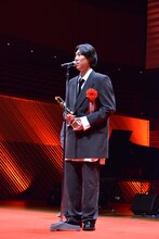 トロフィーを手にスピーチをする野田洋次郎（RADWIMPS）。