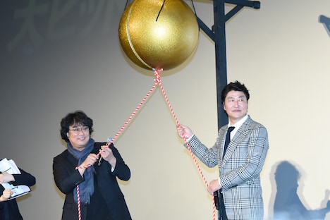 くす玉を割ろうとするポン・ジュノ（左）とソン・ガンホ（右）。