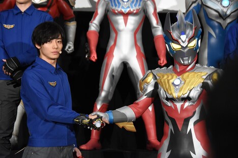 握手を交わす井上祐貴（左）とウルトラマンレイガ（右）。