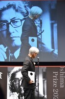 スクリーンに映る大島渚を見る坂本龍一。