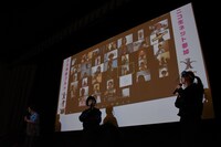 スクリーンにリモート舞台挨拶の視聴者が映し出される場面。