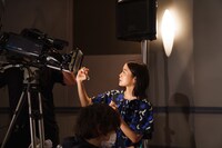 中継先の劇場にいるファンに向けて、サインをする深川麻衣。