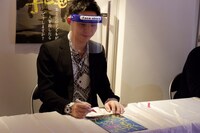 パンフレットにサインをする上村侑。