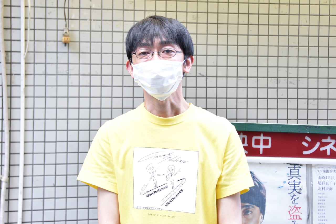 田中俊介がデザインしたシネマスコーレ応援Tシャツを着た坪井篤史。