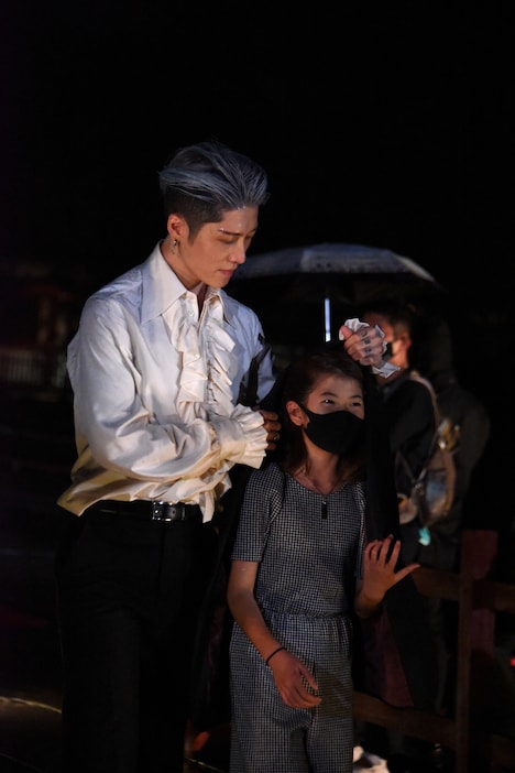 娘を雨から守るMIYAVI（左）。