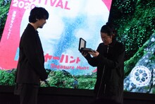 斎藤工（左）からバッジを受け取った永瀬正敏（右）。