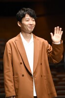 照れ笑いをしながらムービーカメラに手を振る星野源。