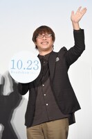 手持ちパネルと左手を振る三木孝浩。