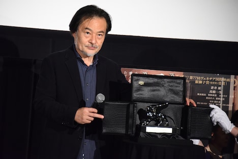 黒沢清と銀獅子賞のトロフィー。