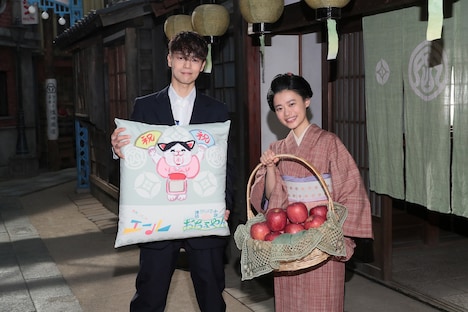 特製座布団を持つ窪田正孝（左）と、福島産の木成り完熟りんごを受け取った杉咲花（右）。