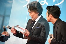 トロフィーを受け取った役所広司（左）。