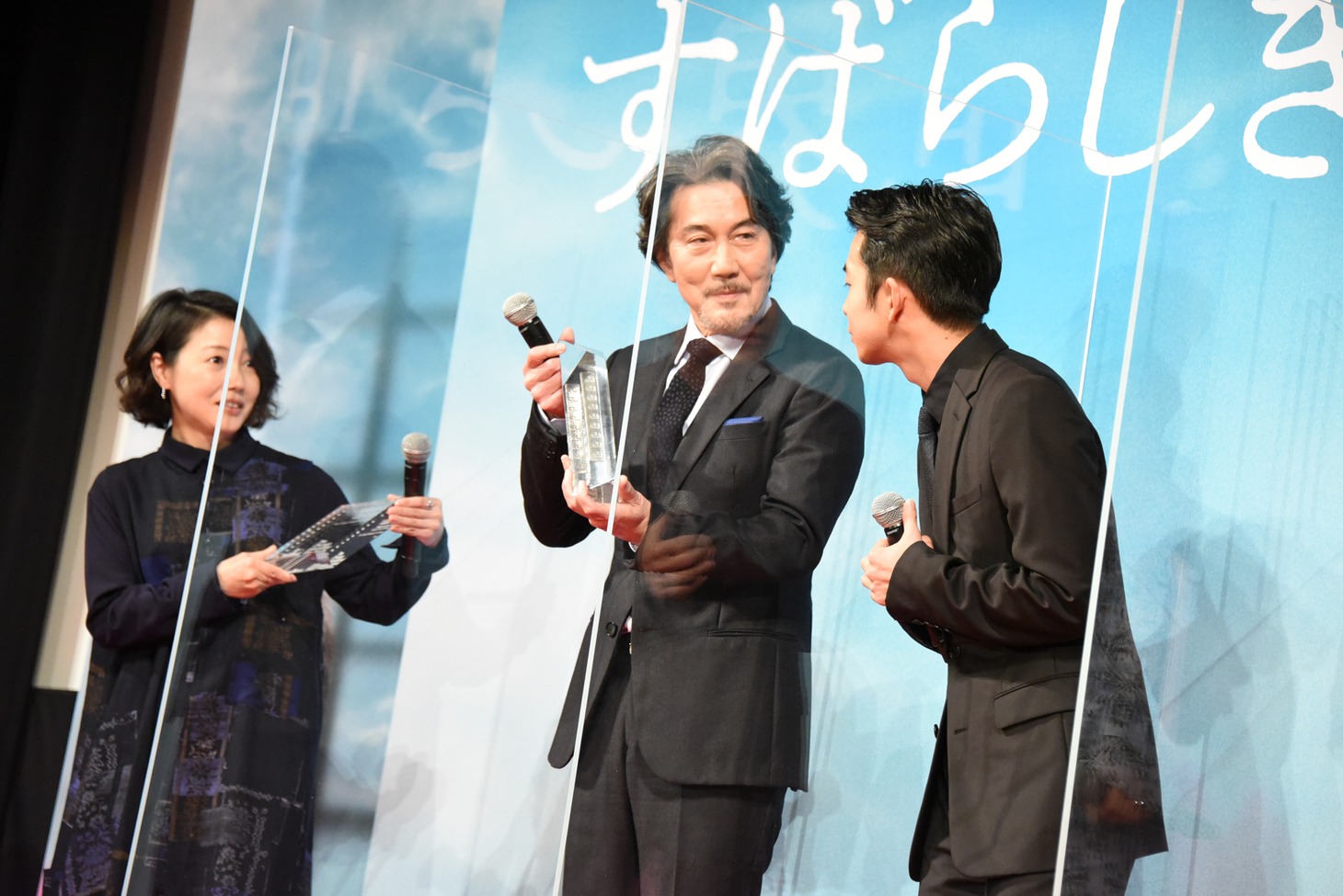 盾を受け取った西川美和（左）と、トロフィーを受け取った役所広司（中央）。