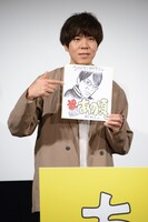 劔樹人が描いた自身の似顔絵を手にするコカドケンタロウ。