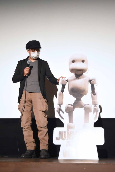 パートンのパネルに手を置く堀貴秀。劇中でパートンの身長は140cmと想定されており、パネルはその高さとなっている。