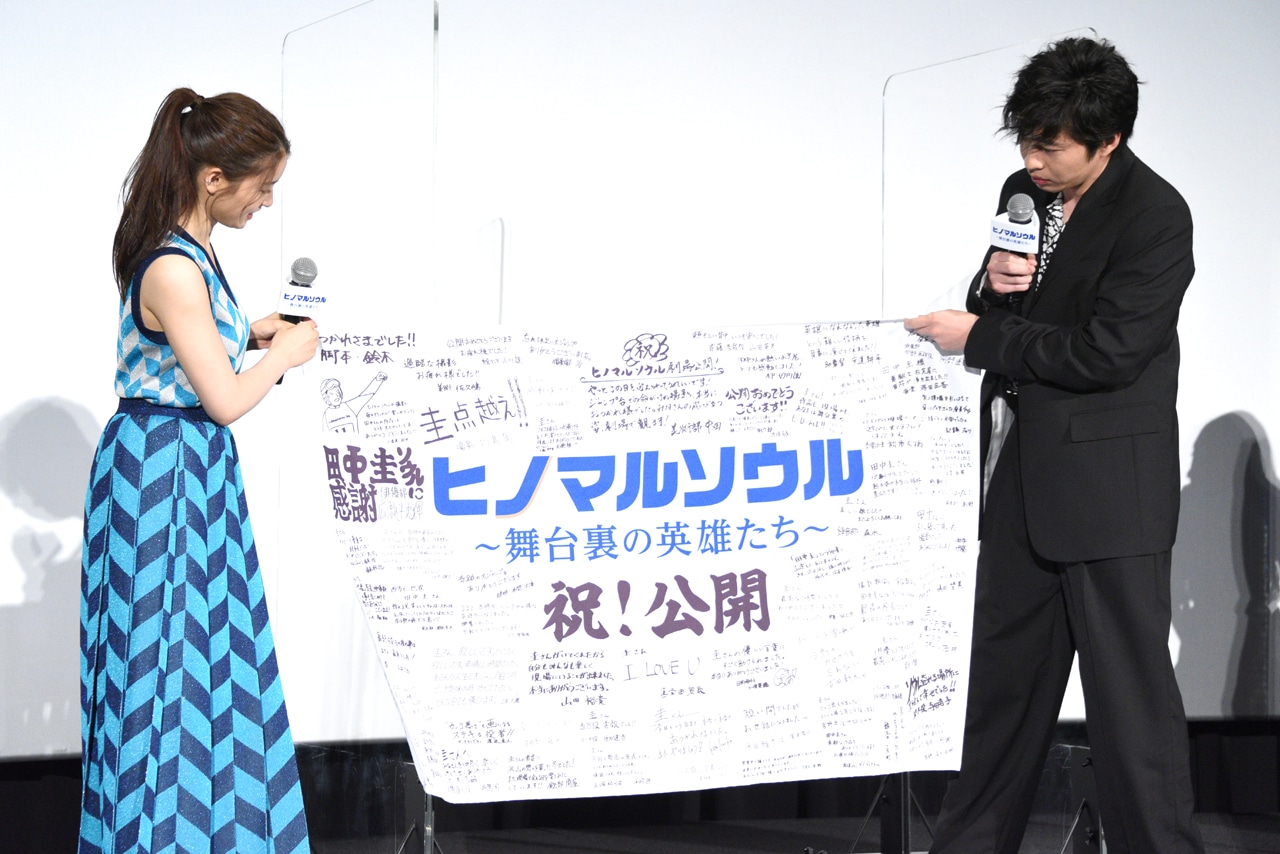 フラッグを広げる田中圭（右）と土屋太鳳（左）。