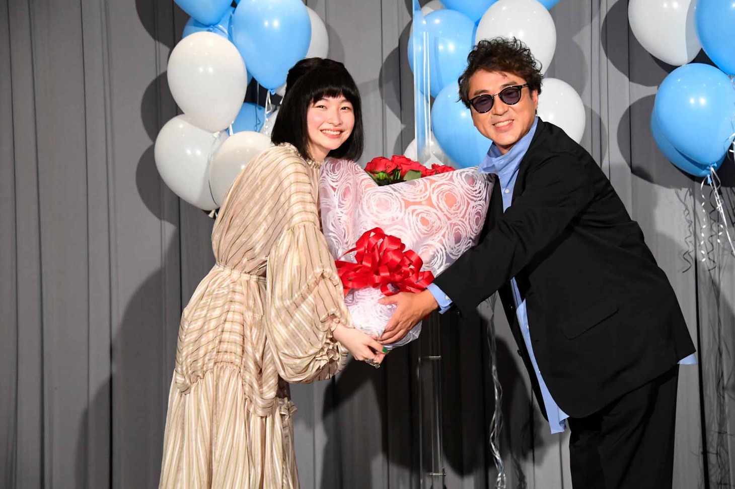 中田乃愛（左）からバラの花束を受け取るムロツヨシ（右）。