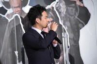 天狗の鼻に邪魔されながらペットボトルで飲み物を飲む様子を再現する三浦貴大。