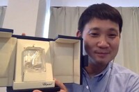 第74回カンヌ国際映画祭で受賞した脚本賞のトロフィーを見せる濱口竜介。