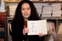 サイン入り原作本を持つ又吉直樹。