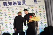 花束を受け取る鈴木亮平（右）。