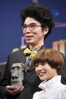 フォトセッション時に、モiPhoneをこっそりアピールする片桐仁。