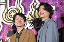 ムービーカメラに向かって百目鬼の弓を引くポーズをしたあと、笑い合っていた神木隆之介（左）、松村北斗（右）。