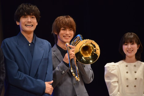 神尾楓珠（中央）がトロンボーンごとギュウギュウ詰め寄り、焦ったようなリアクションをする佐野晶哉（左）。