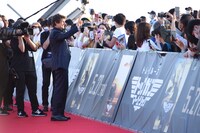 ファンの写真撮影にピースで応じるトム・クルーズ。