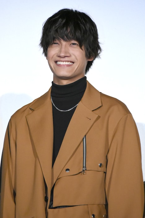 カメラマンから笑顔をリクエストされ、照れ笑いを浮かべる佐野晶哉。