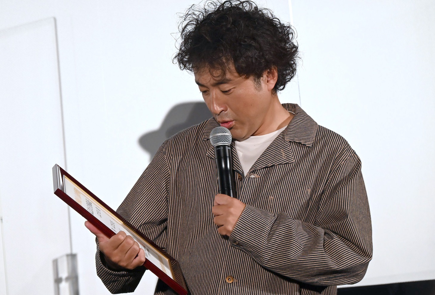 「ムロツヨシの日」認定証をしみじみと眺めるムロツヨシ。