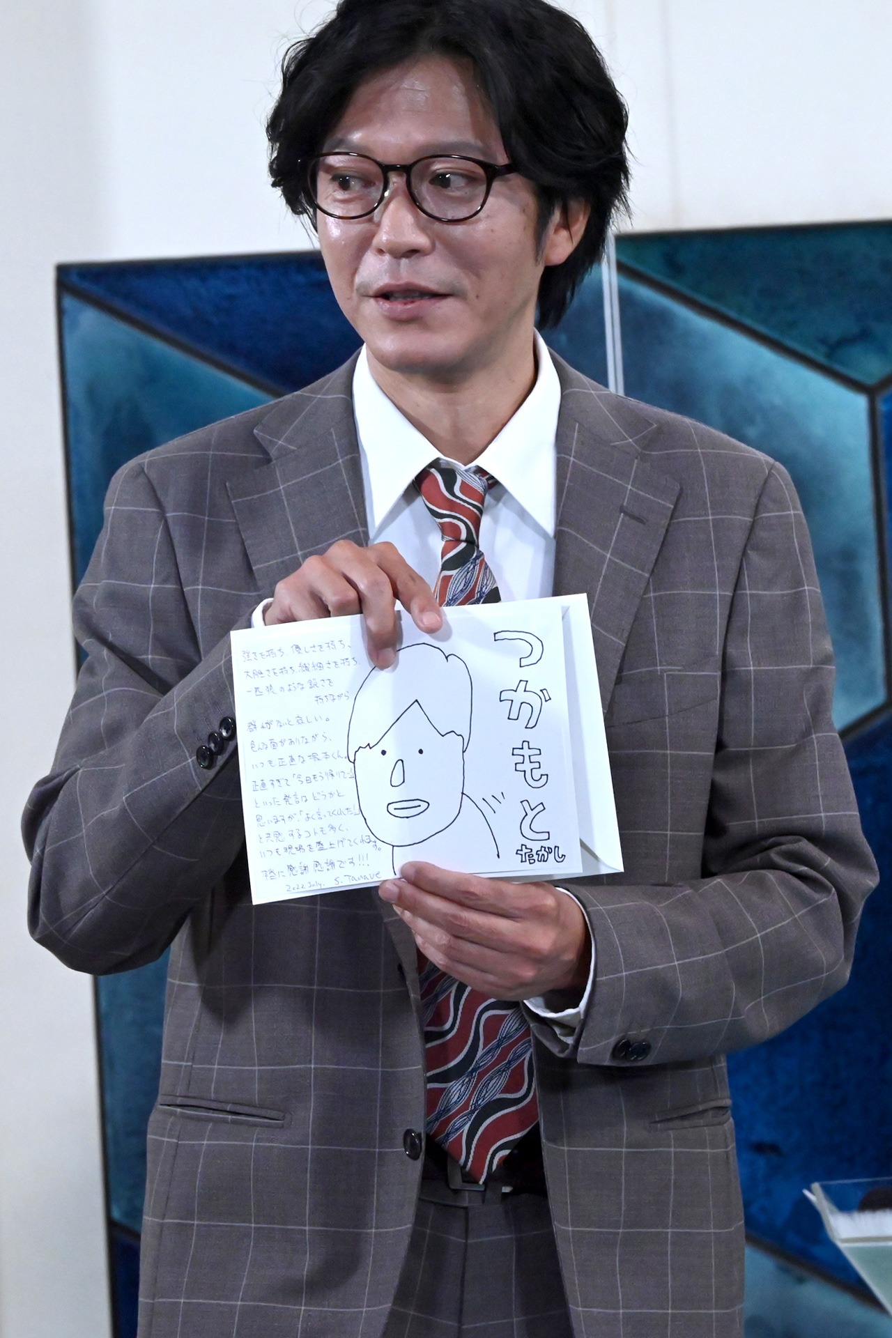 塚本高史への似顔絵入りメッセージカードを見せる田辺誠一。