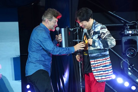 杉山すぴ豊(右)が着ている「ロード・オブ・ザ・リング」Tシャツの指輪に反応するアンディ・サーキス(左)。