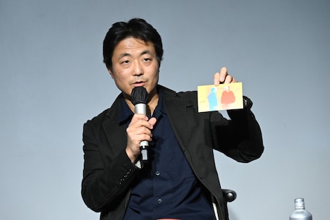 フレデリック・ワイズマンとロバート・クレイマーが対談した際の写真を使用したカードを手にする舩橋淳。