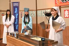 巨大お好み焼きの反転に挑もうとする綾瀬はるか（手前）と、対決相手のチュートリアル（奥）。