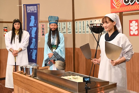 巨大お好み焼きの反転に挑もうとする綾瀬はるか（手前）と、対決相手のチュートリアル（奥）。