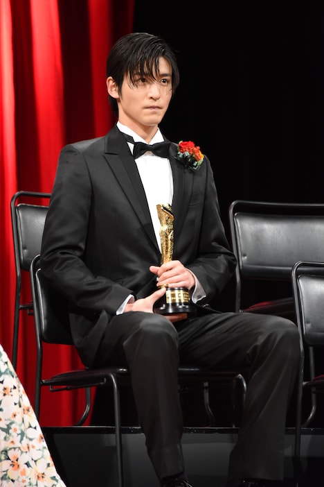 トロフィーを手に、緊張気味に座る目黒蓮。