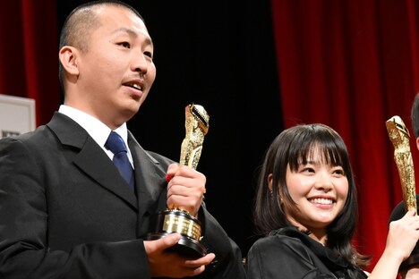 トロフィーを掲げる岸井ゆきの(右)と三宅唱(左)。