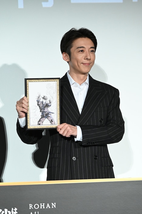 荒木飛呂彦が本作のために描き下ろしたイラストの複製原画を持つ高橋一生。