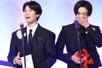 ジョン・カビラの生実況に大喜びの萩原利久（左）と、その姿に笑いをこらえる八木勇征（右）。