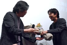 イ・チャンドン（左）に花束を手渡す仲野太賀（右）。