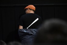 バットがプリントされた映画オリジナルTシャツを見せる白石晃士。