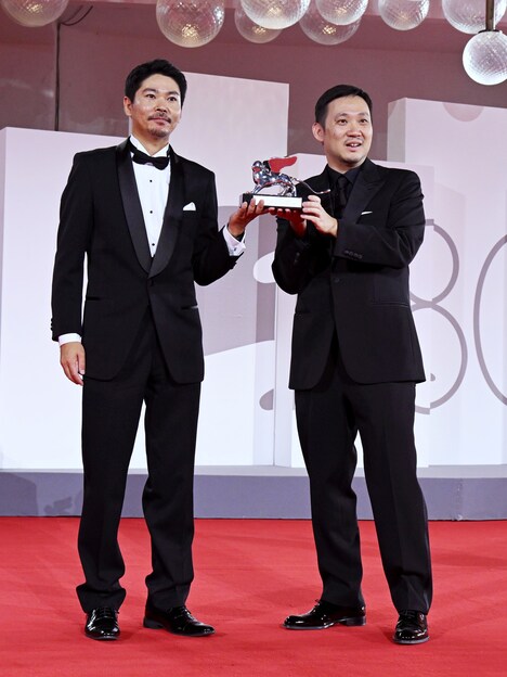 「悪は存在しない」で銀獅子賞（審査員大賞）を受賞した濱口竜介（右）。左は主演の大美賀均。（写真提供：Pool Photo Events 02IPA / Sipa USA / Newscom / ゼータ イメージ）