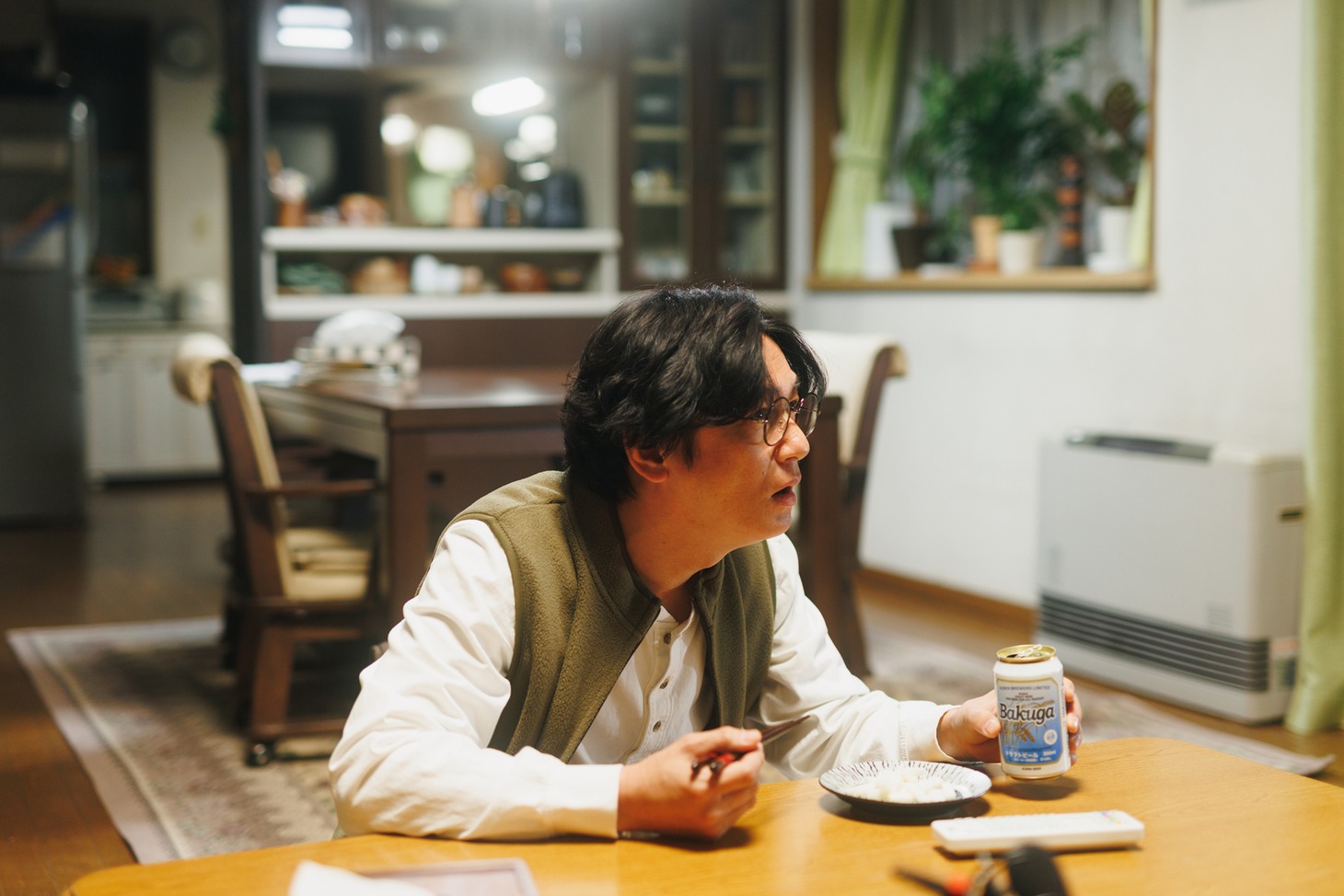 「人生に詰んだ元アイドルは、赤の他人のおっさんと住む選択をした」新場面写真より、ビール片手にテレビを観るササポン。