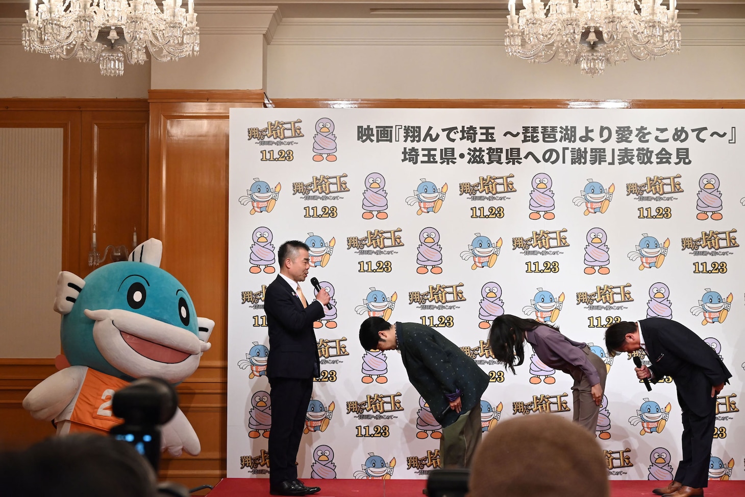 「翔んで埼玉 ～琵琶湖より愛をこめて～」表敬会見にて、滋賀県知事の三日月大造（中央左）に謝罪する様子。