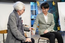 イベント中、自然な動作でペットボトルのキャップを開けて山田洋次（左）に手渡すグー・シャオガン（右）。